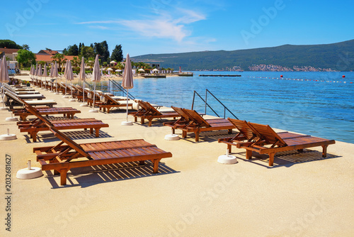 Beach vacations. Waiting for summer and resort preparation. Coast of Bay of Kotor with chaise lounges and beach umbrellas. Montenegro, Tivat