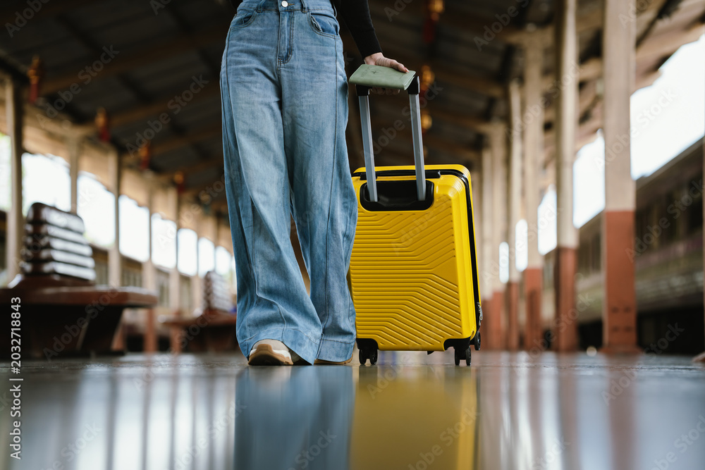 Obraz premium Traveler walking through a train station with a yellow suitcase and passport, representing tourism, transportation, and modern travel lifestyle.
