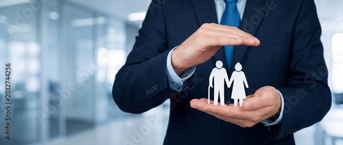 Businessman hands protecting an elderly couple paper cutout representing life insurance and retirement