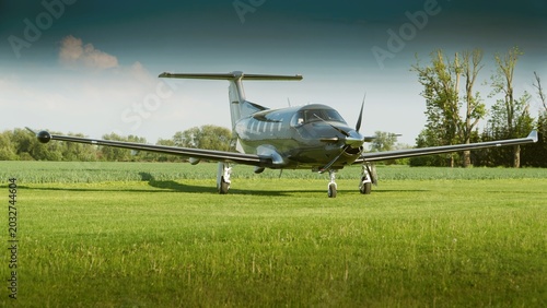 There is a nice propeller plane on the grass of the airport, no people.