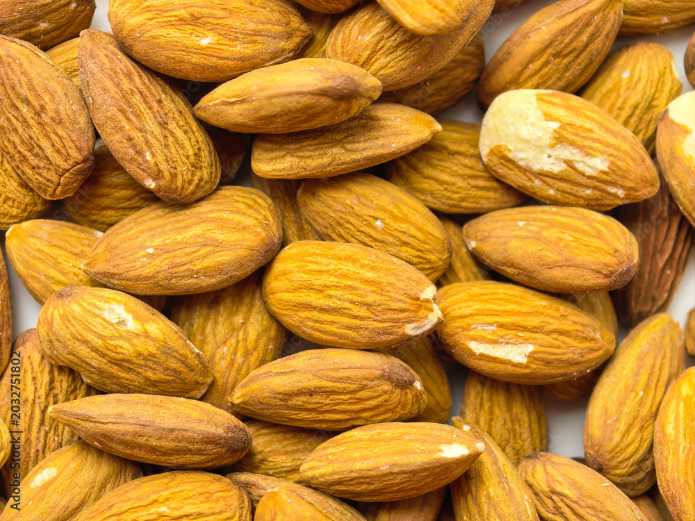 Fototapeta premium Pile of raw almonds shown in close up with visible texture and natural warm tones. Healthy snack ingredient