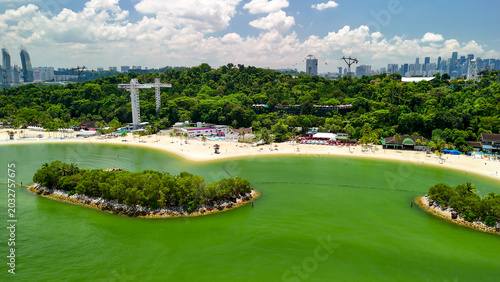 Fotografi Drone view of Sentosa Beach with ocean waves, sunbathers, and vibrant beachfront
