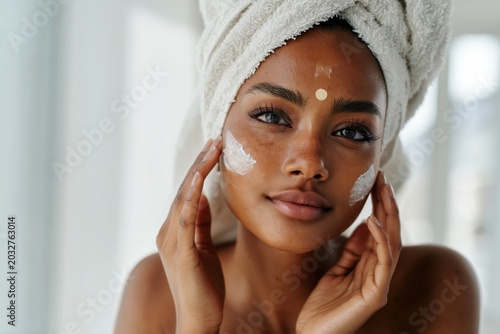 Young South Asian woman enhances beauty with bindi and skincare in a serene bright space