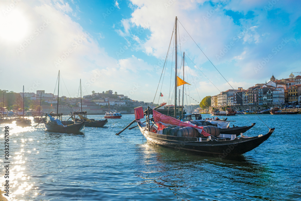 Fototapeta premium Rabelo boats on Douro River by Porto Ribeira with visible wine company names, barrels and waterfront detail near Dom Luis I Bridge