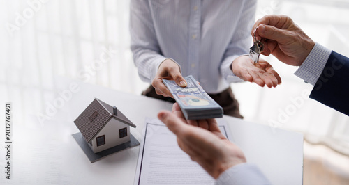 Bild auf Leinwand Client Paying Cash Money for New House and Receiving Keys from Real Estate Agent