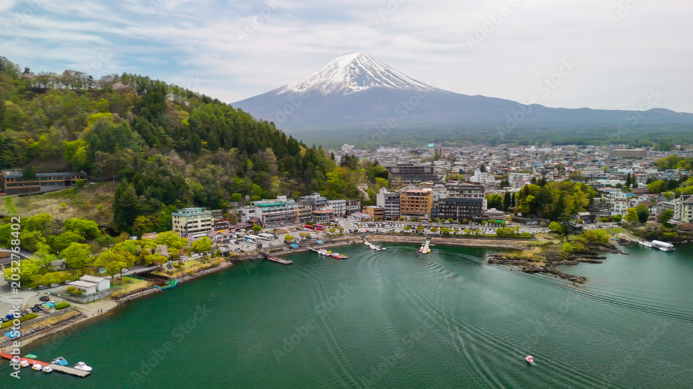 Obraz premium Scenic drone view of Mount Fuji rising behind the calm waters of Lake Kawaguchiko
