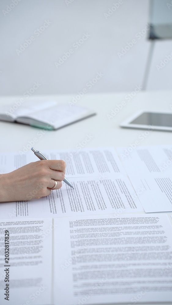 Fototapeta premium Businesswoman signing legal document on an office desk, reviewing terms of a contract or agreement before endorsing it, completing an important corporate transaction