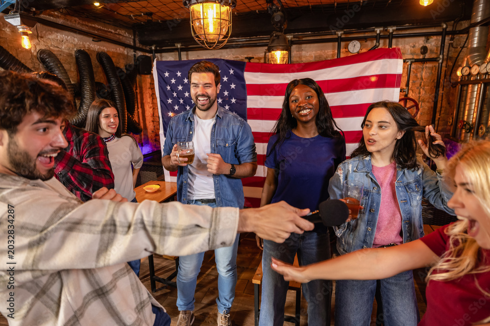 Obraz premium Group of friends fully immersed in karaoke singing in pub