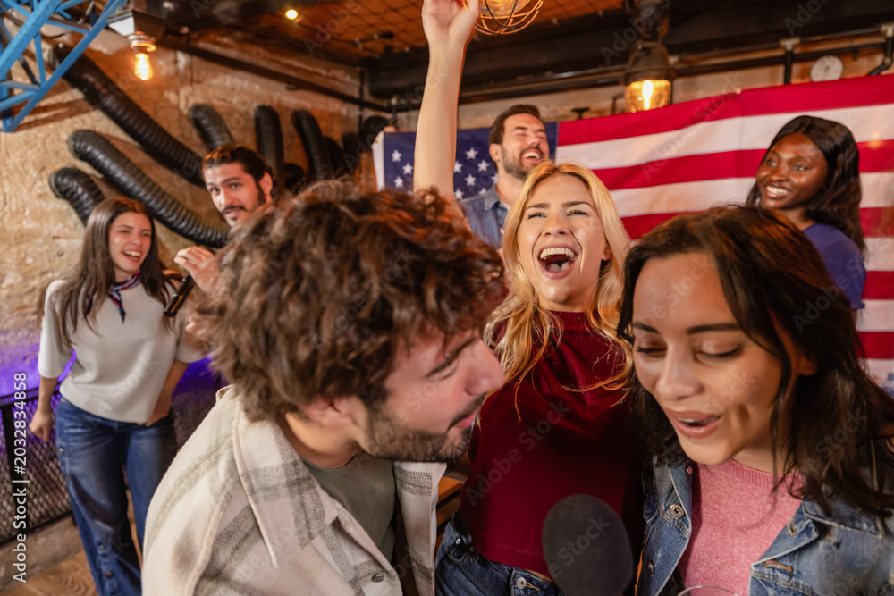 Fototapeta premium Energetic karaoke party with friends and American flag in pub