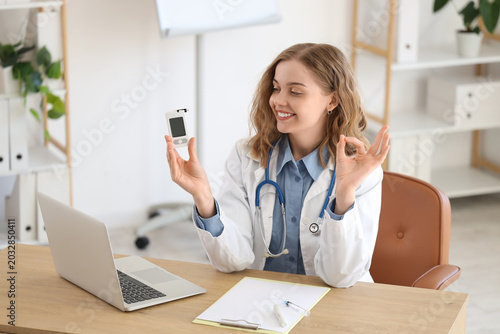 Female doctor with glucometer giving online consultation in office