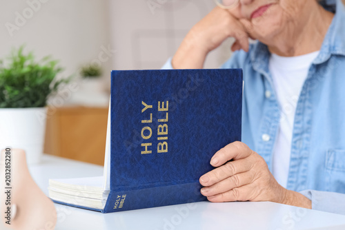 Senior woman reading Bible ...