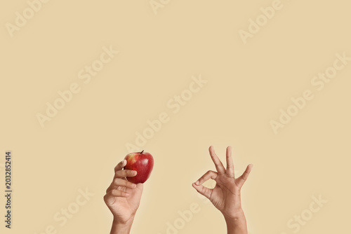 Schilderij op canvas Child with apple showing OK on beige background