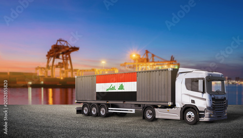Photos Iraq Flag Shipping Container on Truck at Port: A modern semi-truck carrying a shipping container adorned with the Iraq flag is parked at a busy port terminal