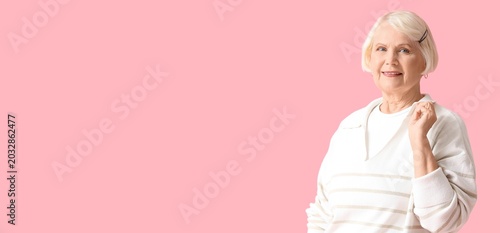 Senior woman in sweater on pink background with space for text