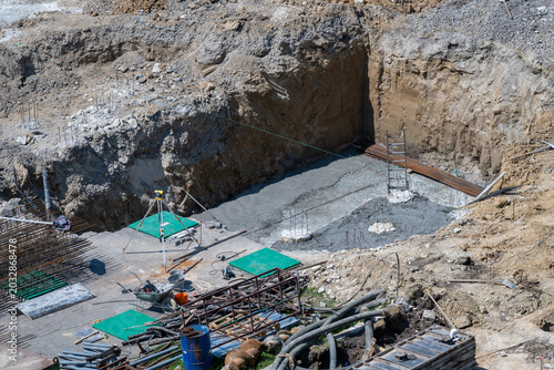 Obraz na plátně a deep construction excavation pit where a fresh concrete foundation pad and vertical steel rebar reinforcements have been laid