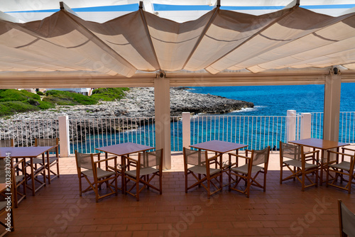 Bild auf Leinwand Luxury restaurant terrace with awning canopy overlooking the blue Mediterranean sea and rocky coast