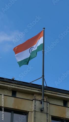 Indian flag waving on tall pole against blue sky with clouds