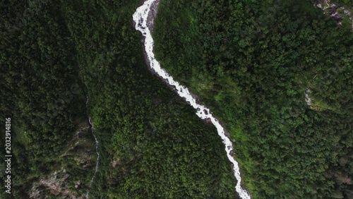 Aerial view of mountain river between forest in lowland between mountains
