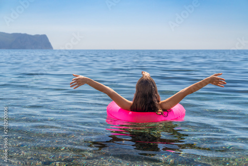 Vászonkép Summer vacation floating Young woman in a pink swim ring enjoys the calm blue oc