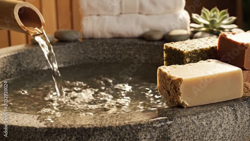 Water flowing from bamboo spout into stone basin