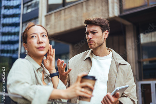 Young Couple Arguing Over Coffee and Tablet Outside in Urban Business District