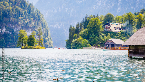 Canvas Print Lake view with boats, trees, and houses near mountains in summer with clear sky