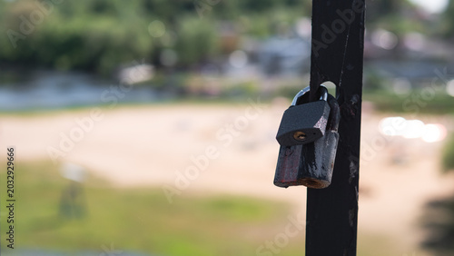 Quiet Lock On Seaside. Tranquil Lock Attached To Railing By Peaceful Shoreline. Serene Lock On Fence Beside Shimmering Water Captures Quiet Summer Atmosphere