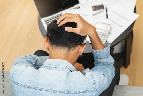Household financial economic concept, Stressed Young Asian adults are looking at credit card bills issued documents, and apartment loan mortgages and worrying about having no money to pay.