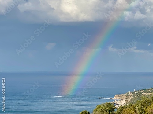 Rainbow over the sea by a rocky coast after rain