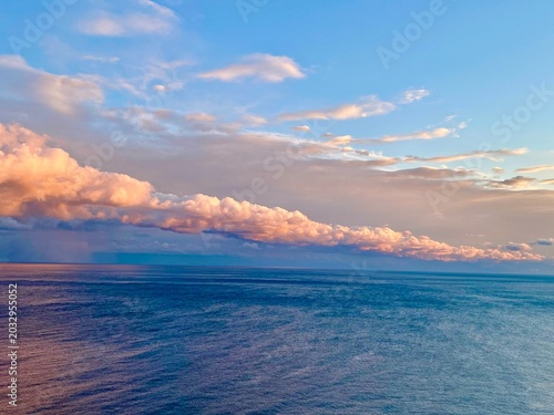Long pink cloud band over calm sea at sunset