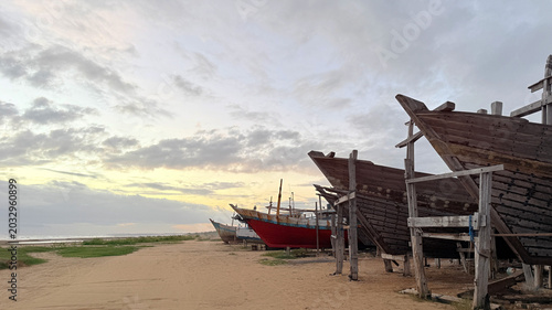 Foto Traditional wooden fishing boats at a coastal shipyard during sunset