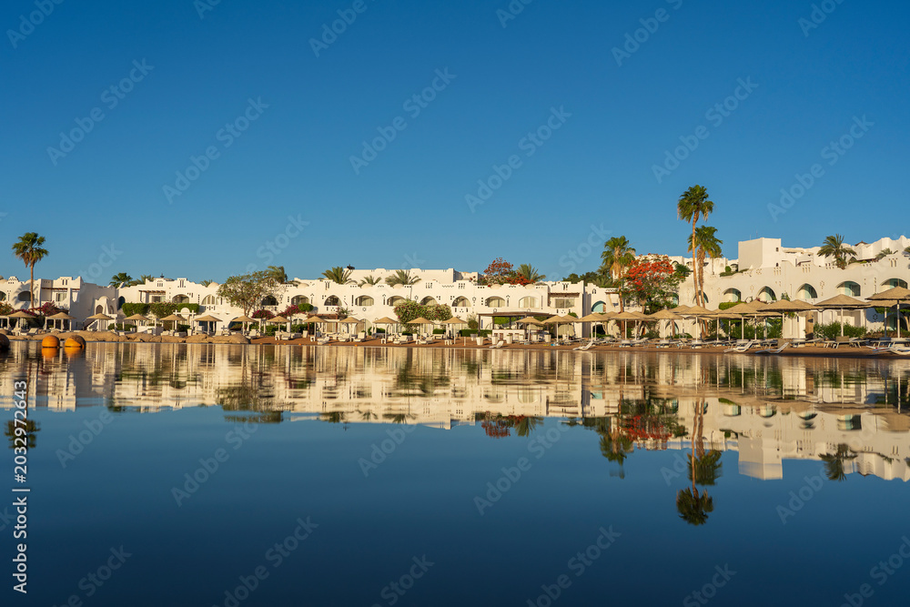 Obraz premium Beautiful panoramic view of a tropical hotel resort on the coast with traditional Arabic architecture perfectly reflecting in mirror-like water, Sharm El Sheikh , Egypt