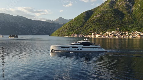 aerial drone side view of explorer superyacht sailing past Perast and islands, Bay of Kotor, Montenegro
