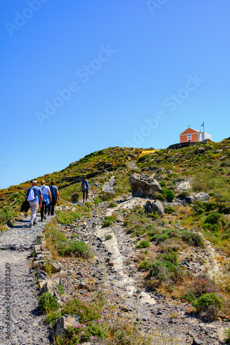 Hikers on Oia to Fira trail with chapel on hillside