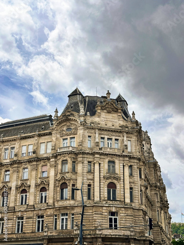 Ornate historic building with detailed classical architecture beneath dramatic clouds. Urban travel and architectural landmark scene in a European city.