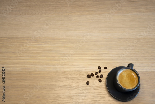 Fotografía Black espresso cup with few scattered coffee beans on wooden surface