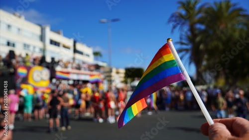 Schilderij op canvas Hand holding a rainbow flag, symbolizing LGBTQ+ freedom and diversity, while cel