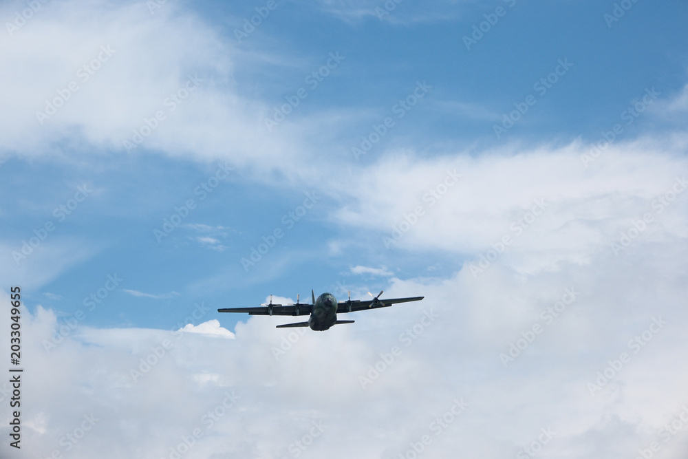 Fototapeta premium Four-Engine Turboprop Military Transport Aircraft Taking Off into Blue Sky with Clouds