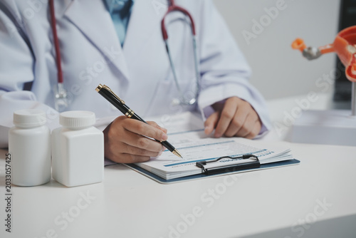 Foto A doctor’s hands are shown writing on a medical record form on a clipboard