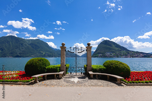 Ornate Iron Gate with Lake Lugano Monte San Salvatore and Red Flowers Switzerland