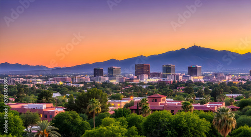 Beautiful sunset over the city skyline with mountains in the background and green trees in the foreground