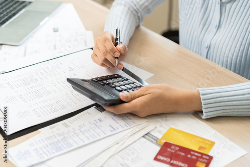 Canvas-taulu Stressed person asian young employee woman hand using calculator to calculate expenses of monthly and checking expenses from bill, receipt on table at home