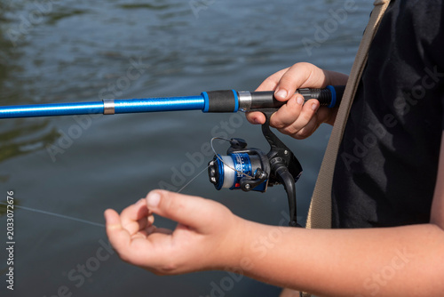 Newbury Berkshire England UK. 23.06.2026. A child's hands are shown holding a blue fishing rod and reel, ready to cast into the water