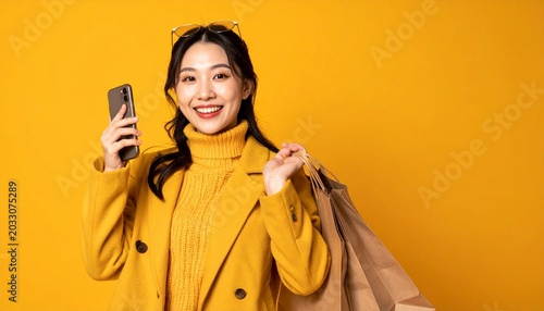 Stylish Asian Woman with Shopping Bags and Phone on Yellow Background.