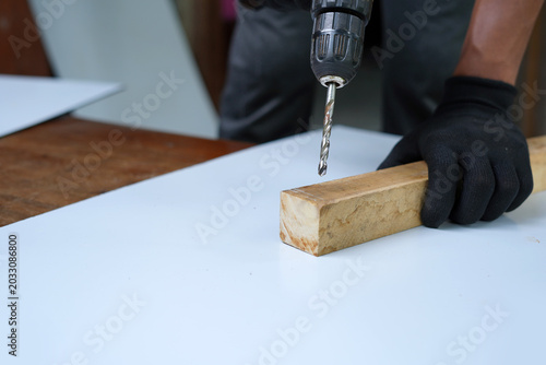 Man with drill into wood piece closeup image