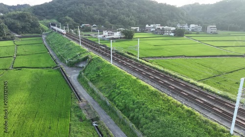 High speed train passing through green rice fields.