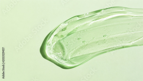 transparent green gel smear on light green background. Cosmetic skincare product texture. Moisturizing serum, aloe vera extract or antiseptic sanitizer. Beauty and health care concept