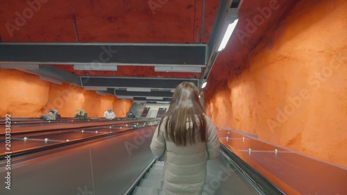 A visually striking subway station characterized by vibrant orange walls and sleek escalators, showcasing a contemporary architectural design. Perfect for urban exploration themes and modern transport