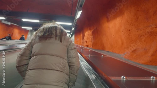 Explore an underground transport station characterized by vibrant red walls and modern architecture. The image captures a person traversing the escalator, highlighting the unique design of this intrig