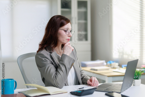 Bild auf Leinwand Professional businesswoman concentrating on her work, sitting at a desk and usin